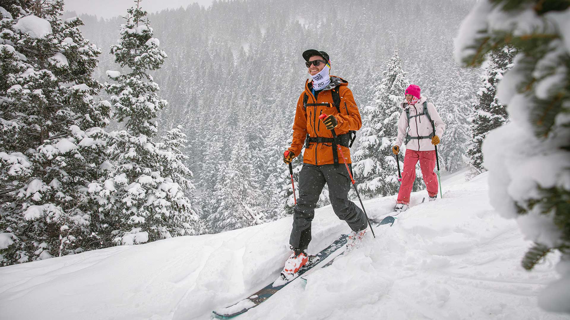Two people skiing through a snowy forest with trees covered in snow.