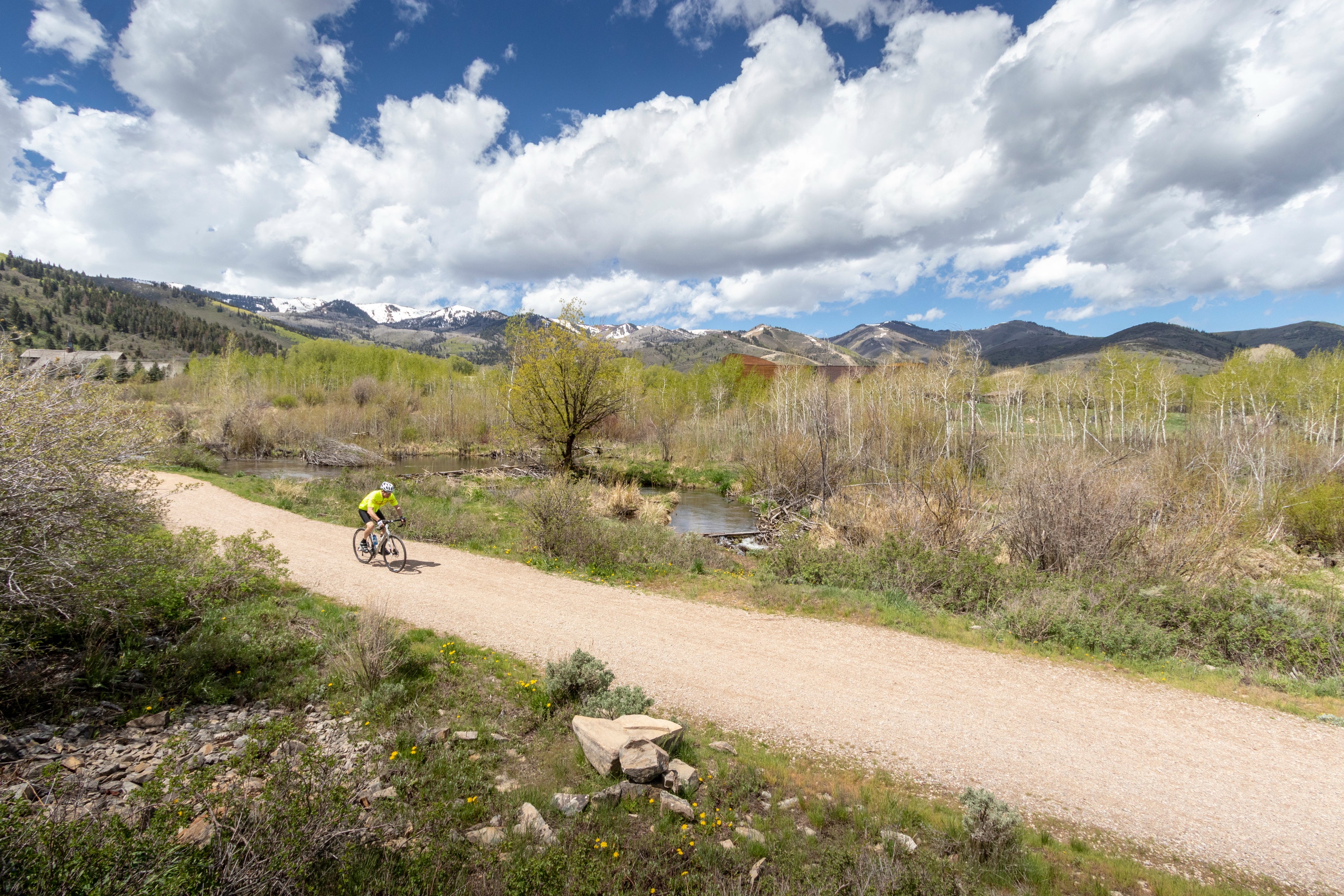 Jans Expert riding a gravel bike on a trail with snow-capped mountains in the background near Park City, Ut