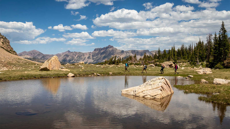 Hikers near a mountain lake with reflections on a clear day
