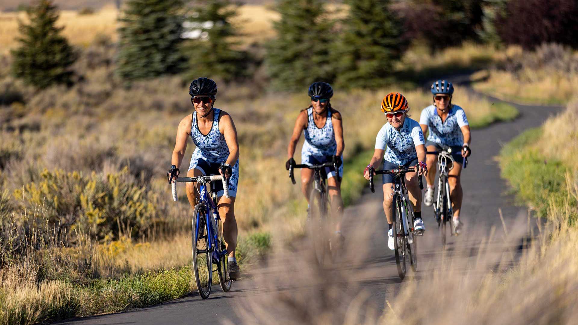 Four cyclists in matching outfits riding on a rural road.
