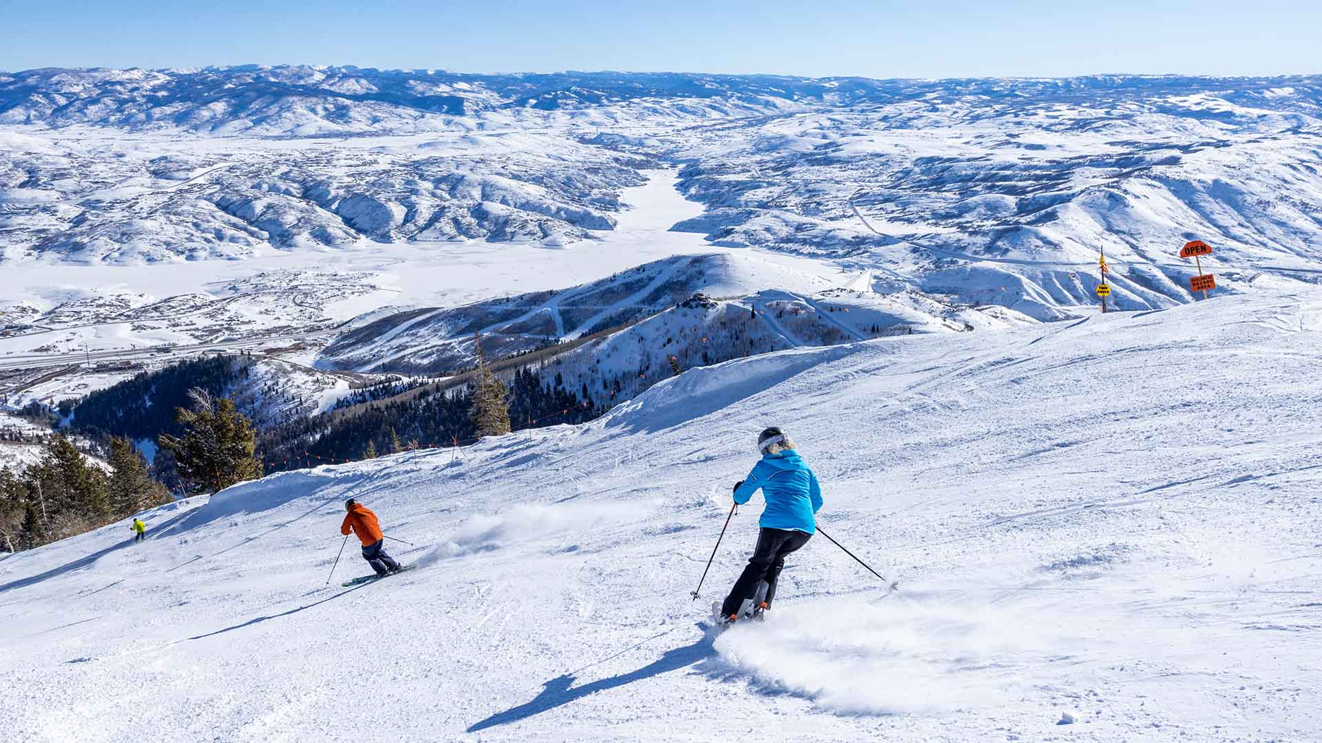 Two skiers on a snowy slope with a scenic mountain landscape in the background.