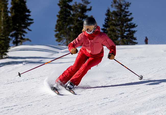 Jans Ski Buyer Cortney Valavane wearing a pink Norrona ski suit while skiing on a groomed run at Deer Valley Resort, Park City, Ut.