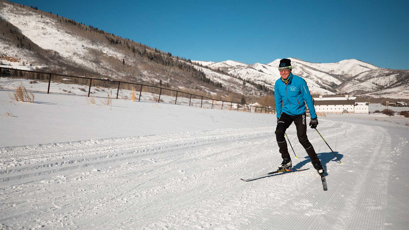 Jans Expert skate skiing on the White Pine Touring Nordic track with mountains and the iconic white barn in the background in Park City, Utah.