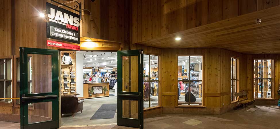 Interior of a store with wooden walls and large windows, featuring a 'Jans' sign.