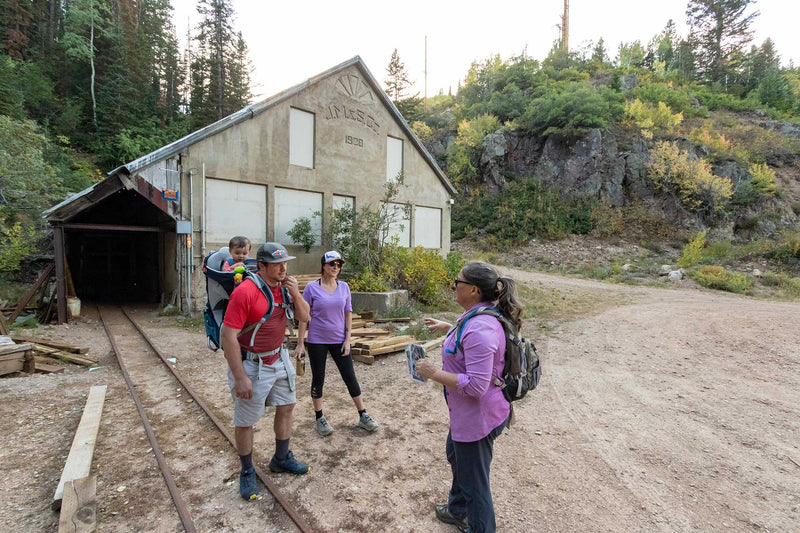 Group of people hiking near a rustic building in a forested area
