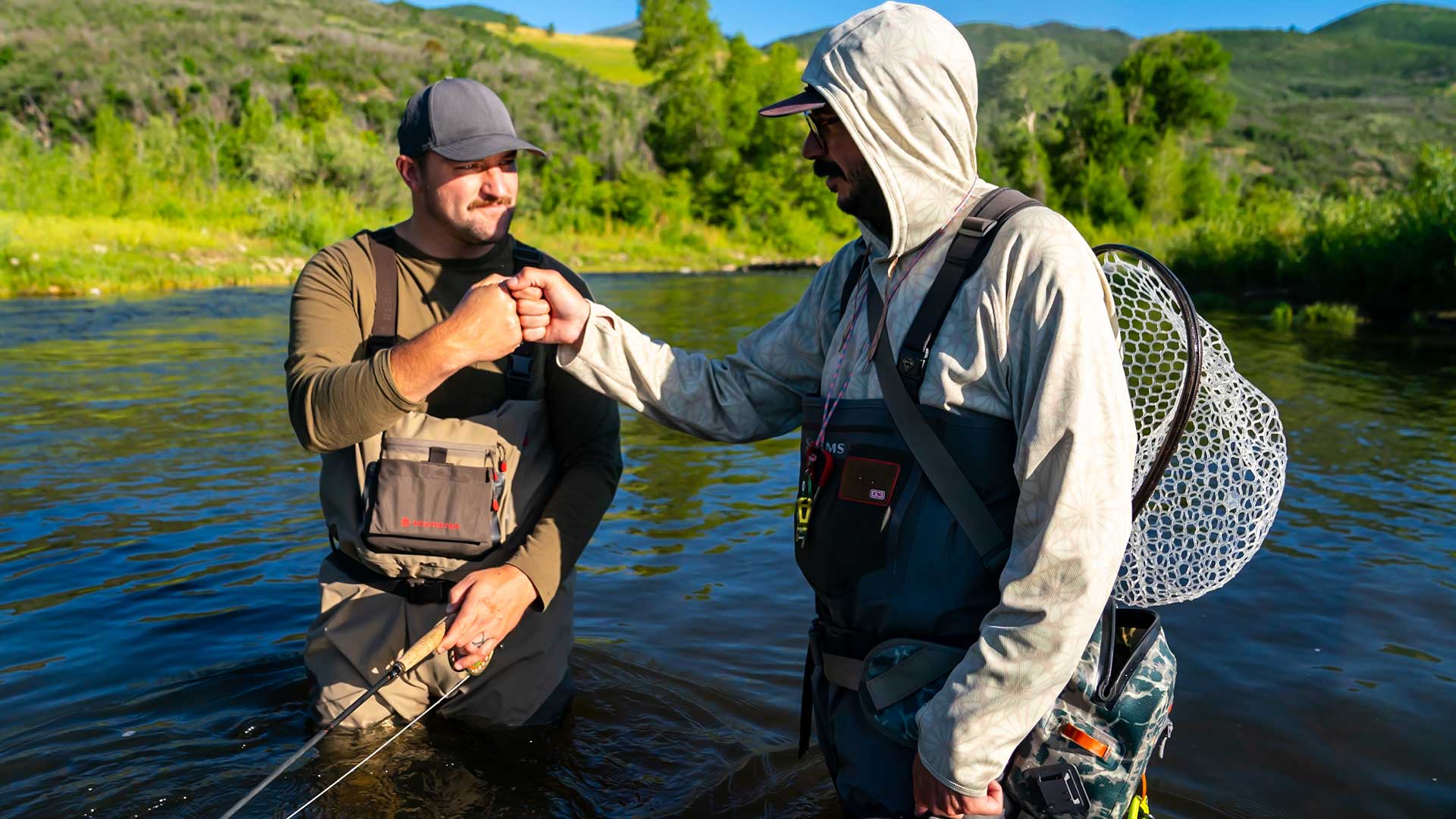 Jans fly fishing guide fist bumps a client after catching a fish on a river near Park City, Utah