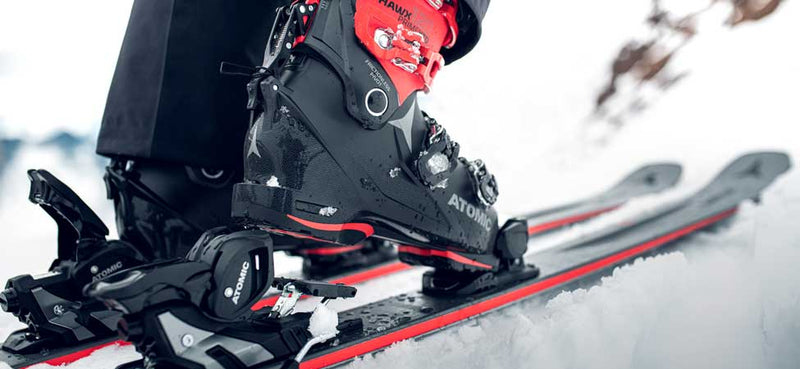 Close-up of a ski boot and skis on a snowy surface