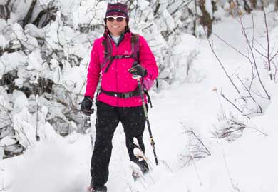 Person in a pink jacket and sunglasses standing in a snowy forest
