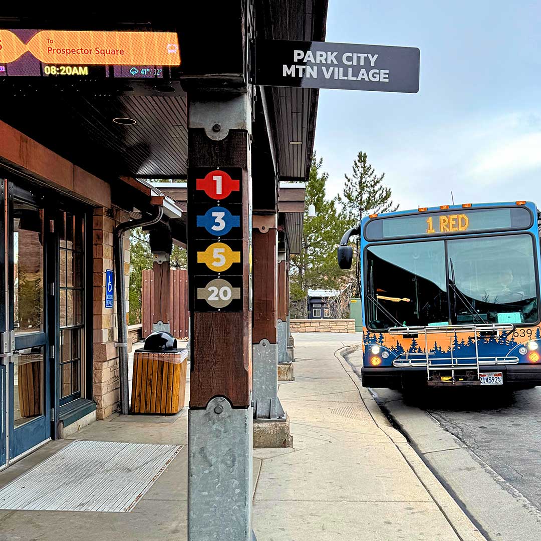Bus at a bus stop with a sign indicating 'Park City MTN Village' and a bus route number.