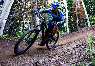 Person riding a mountain bike on a trail with trees in the background