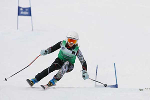 A junior ski racer skiing down a race course at Park City, Utah.