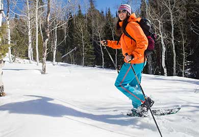 Person snowshoeing in a snowy landscape with trees in the background