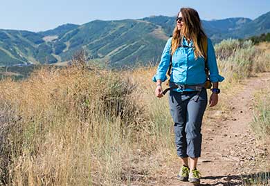 Woman hiking on a trail with mountains in the background