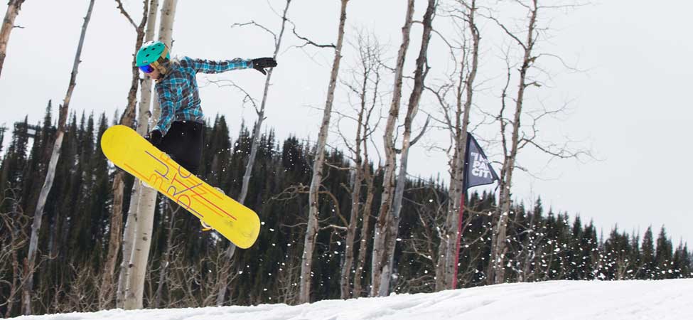 Person snowboarding in a forest with trees and a flag in the background