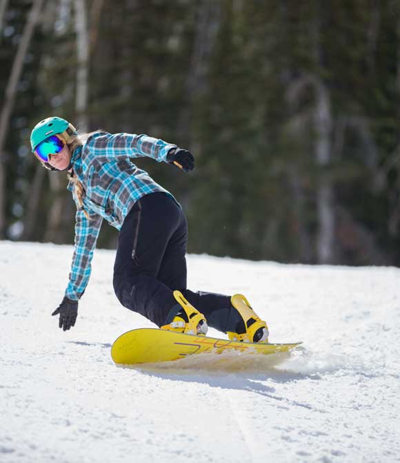Person snowboarding on a snowy slope with trees in the background
