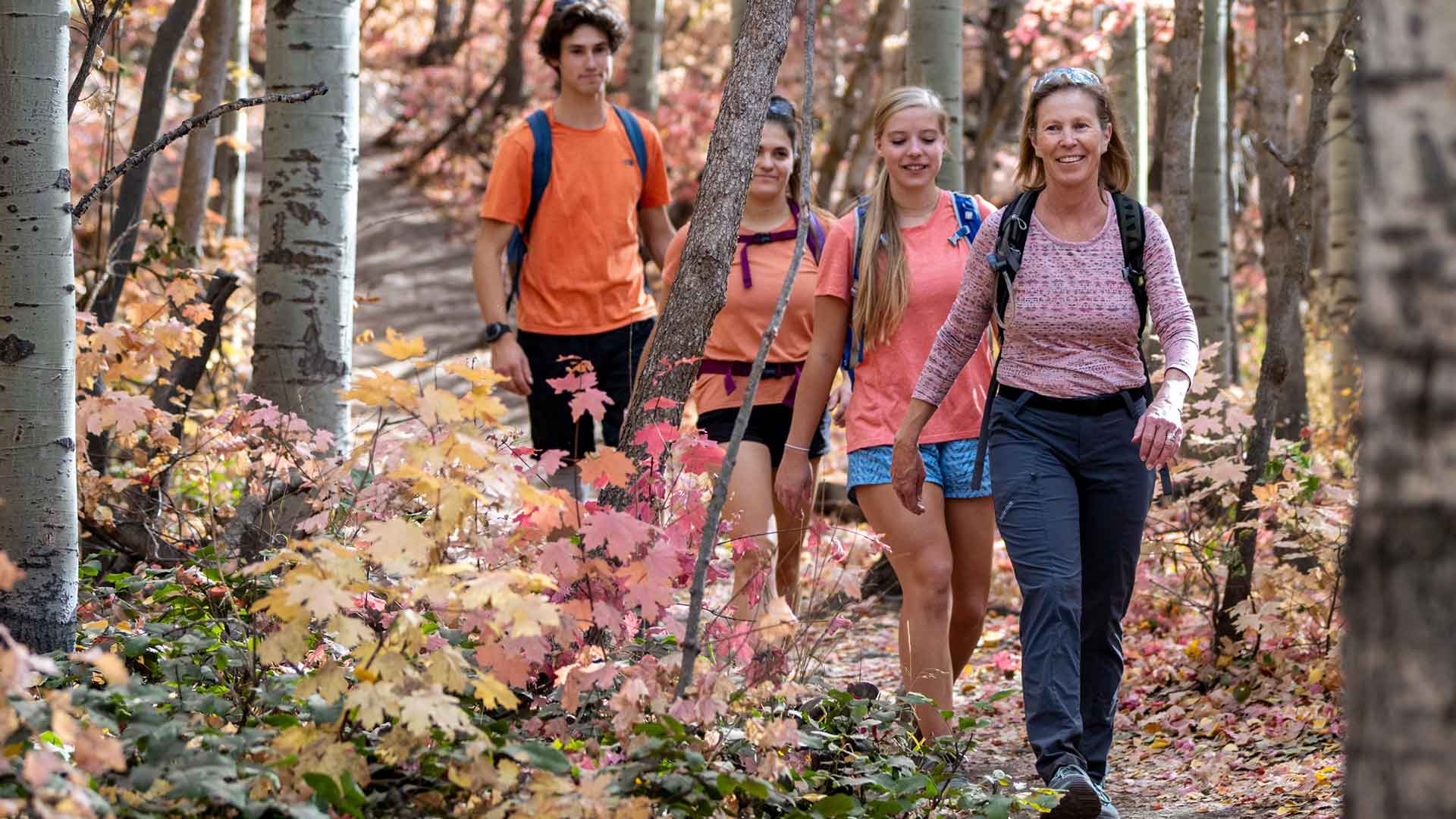 Four people hiking through a forest with colorful foliage