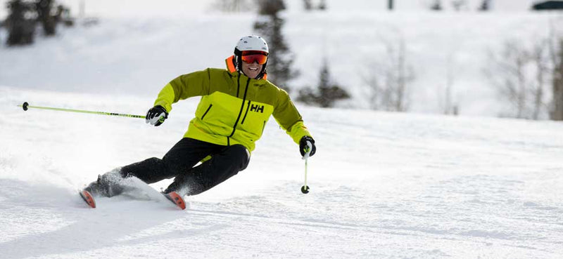 Jans Expert skiing downhill on a snowy slope with trees in the background