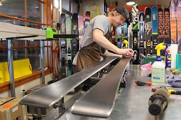 Ski Technician waxing a pair of skis at the Rennstall Tech Center in Park CIty, Utah.