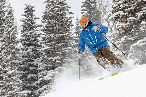 Jans Expert skiing through evergreen trees in powder while it's snowing at Deer Valley Resort, Park City, Utah.