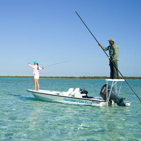 Two people on a boat in clear water with a clear blue sky