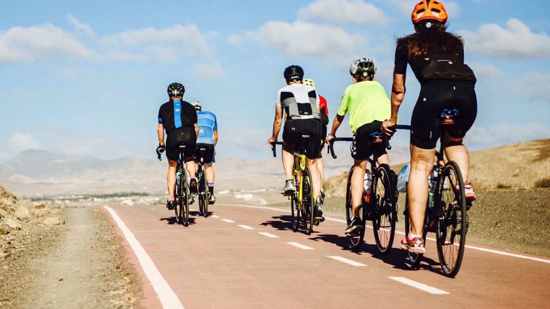 Group of cyclists riding on a road with a clear sky