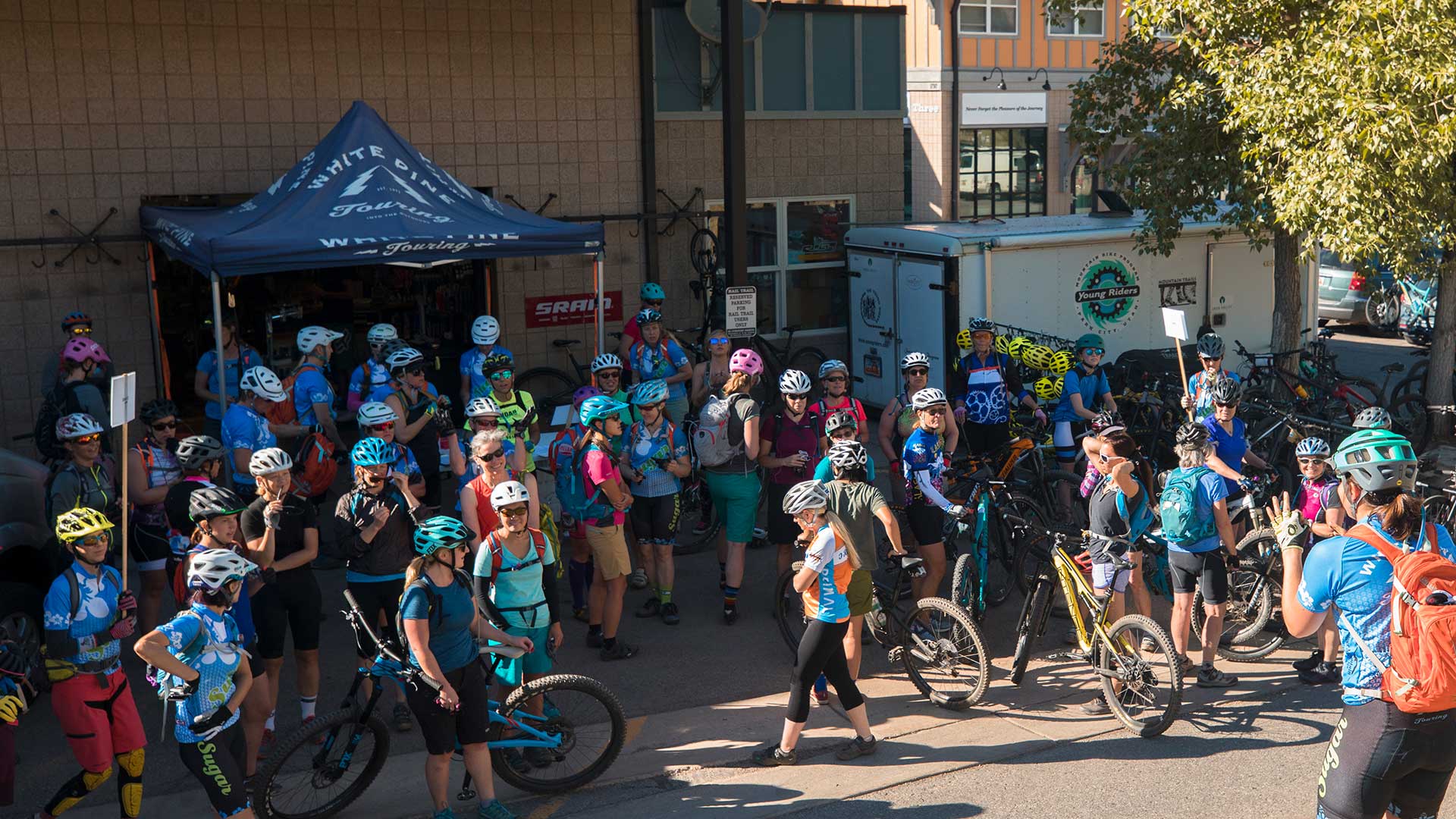 Group of cyclists with bicycles gathered around a tent in an urban setting